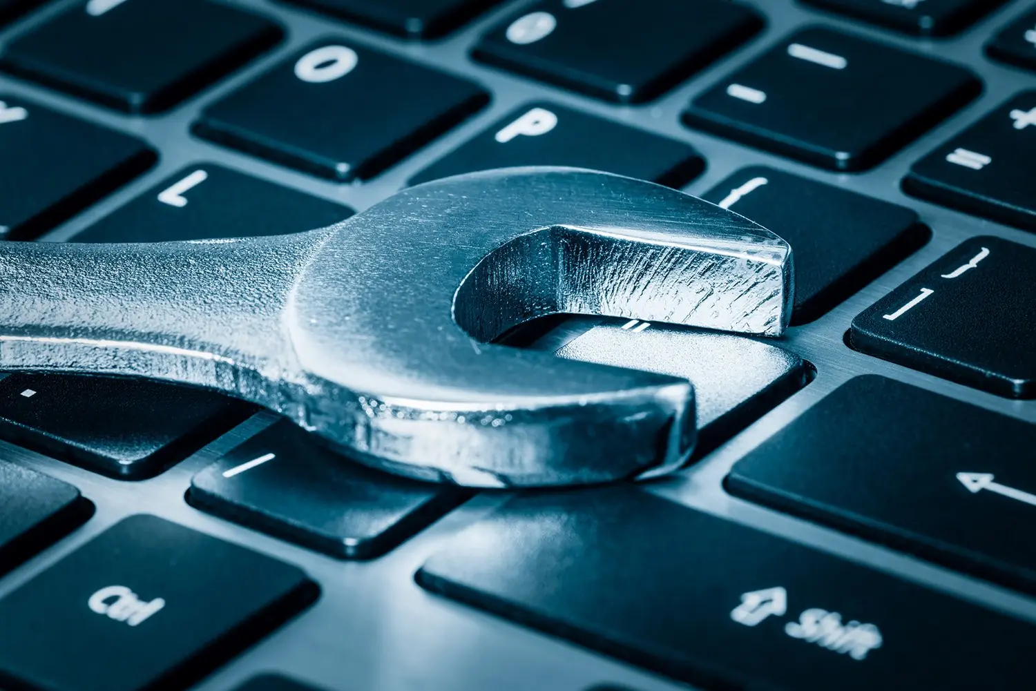 A wrench on top of a laptop keyboard