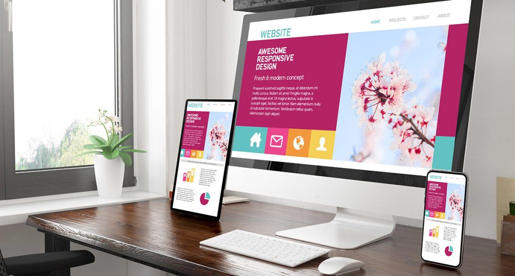 Web Design Services showing an office with a website loaded on a laptop, tablet and mobile device
